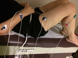 A male patient lies on a treatment table with five electrodes connected by cords placed on his arms and legs