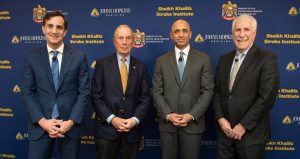 Four men, including President Ronald Daniels, stand in front of a backdrop during the launch of the Sheikh Khalifa Stroke Institute.