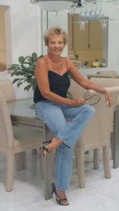 Sharon Henderson sits on a table in her Florida home, posing for the camera.