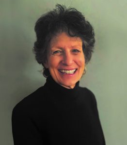 Johns Hopkins Office of Gift Planning Senior Director Anne Doyle smiles and wears a black turtleneck and gold hoop earrings.