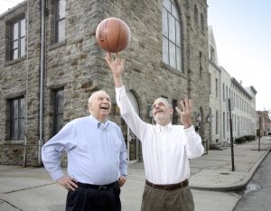 Johns Hopkins School of Medicine alumni and faculty Simeon Margolis and John Boitnott stand on a city corner looking up at a basketball held by Boitnott.