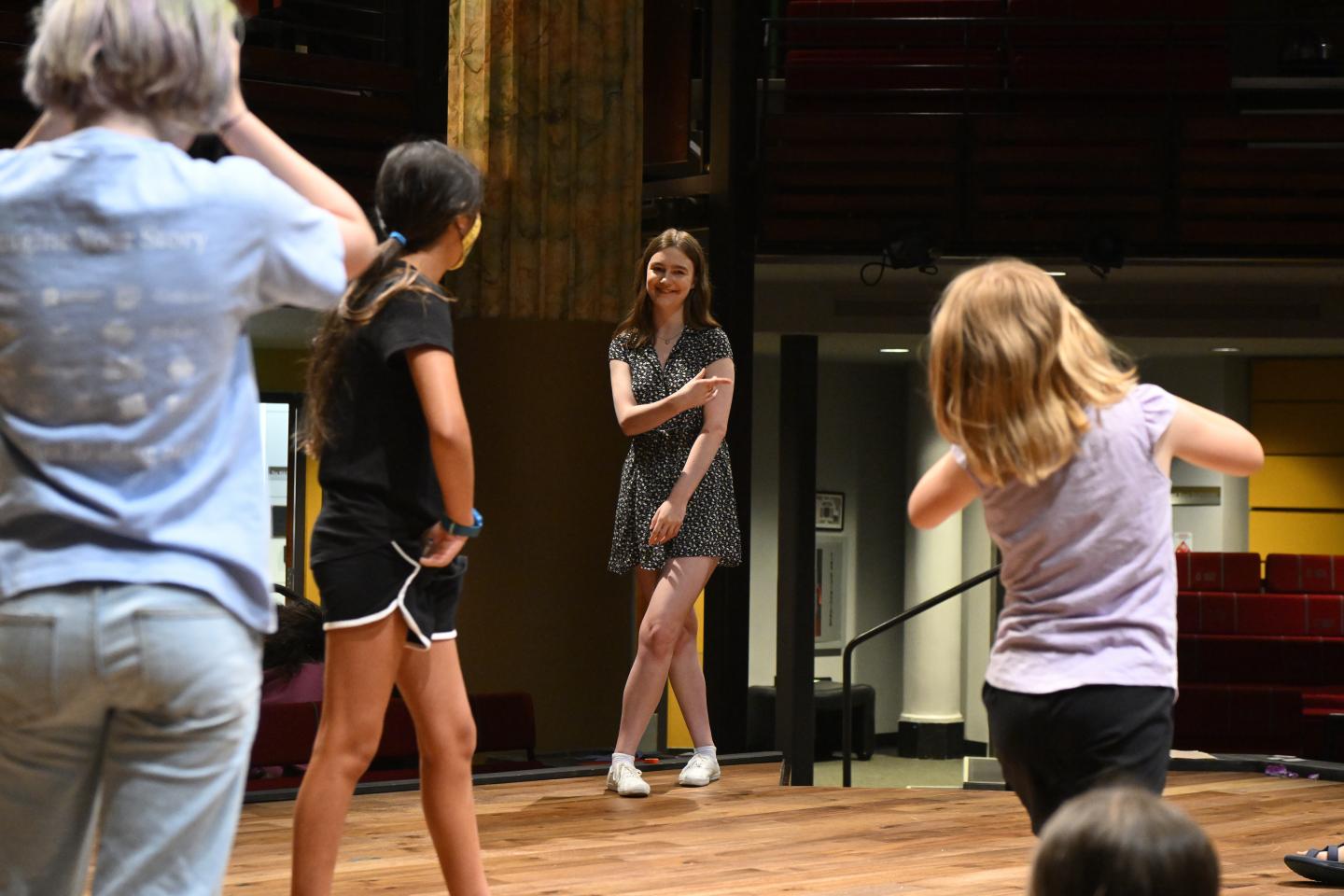 Johns Hopkins student Caroline Colvin stands on a stage with younger students
