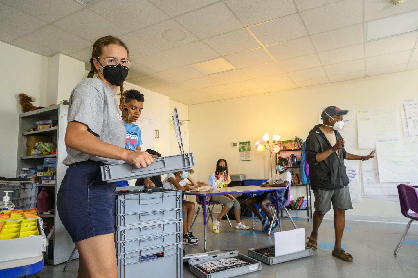 In a mask, Johns Hopkins student Helene Girard hands out supplies at Village Learning Place