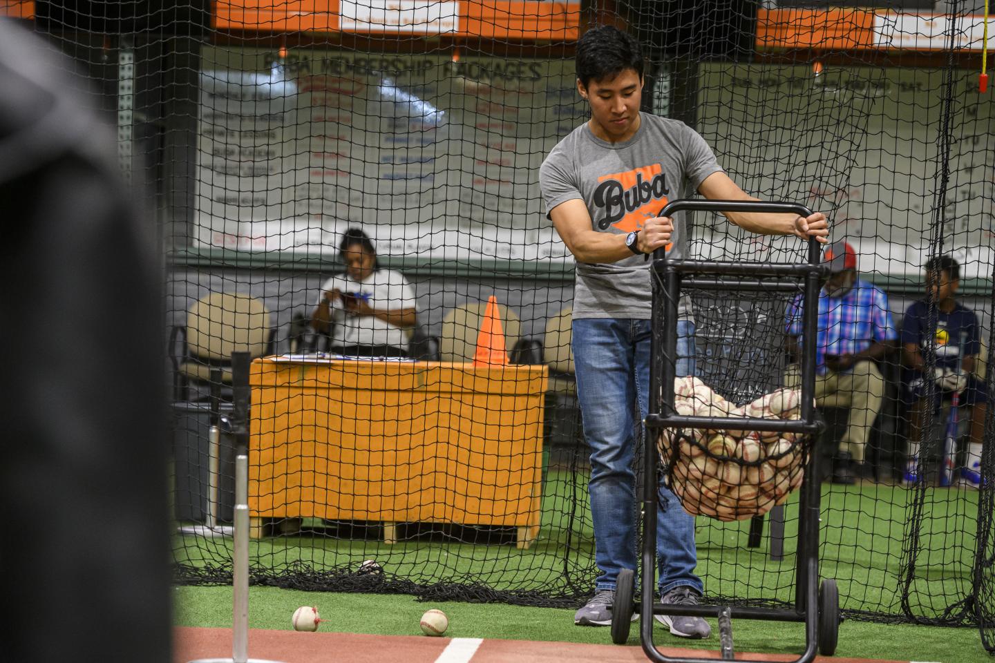 Johns Hopkins student Neal Lim organizes sports equipment on an indoor court