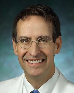 Cardiac surgeon-in chief for the Johns Hopkins Health System James Gammie wears glasses and smiles broadly.
