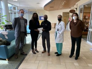 a group of people stands in howard county general hospital's lobby with a check