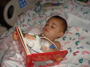Hopkins bladder exstrophy patient evyn weiss reading a book in a hospital bed as a toddler