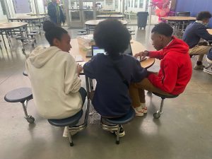 hopkins student mentor Madison McPherson sits at a table with two eighth grade students