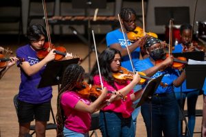 a group of orchkids violinists, including justice gaines, performs