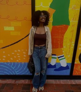 henrietta lacks scholarship recipient eriona birts stands in front of a colorful mural