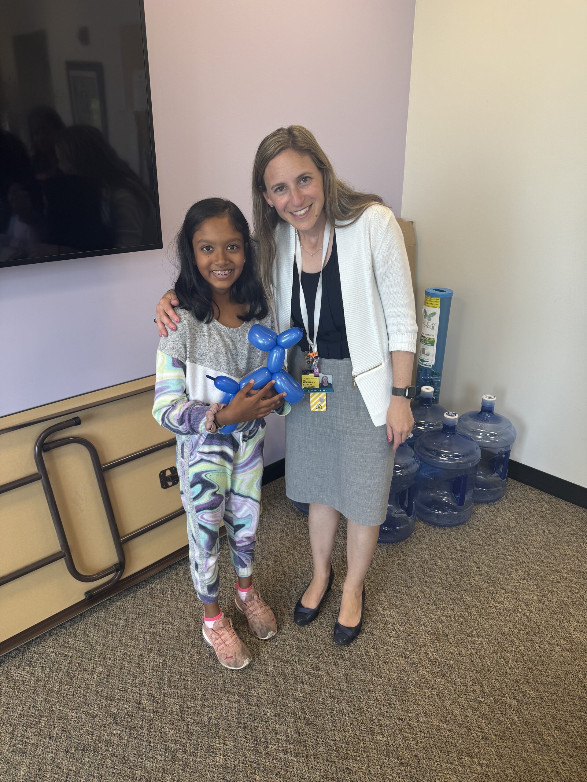 johns hopkins pediatric endocrinologist and camp charm city director dr. risa wolf stands with 10-year-old fundraiser myra saxena, who is holding a blue balloon dog